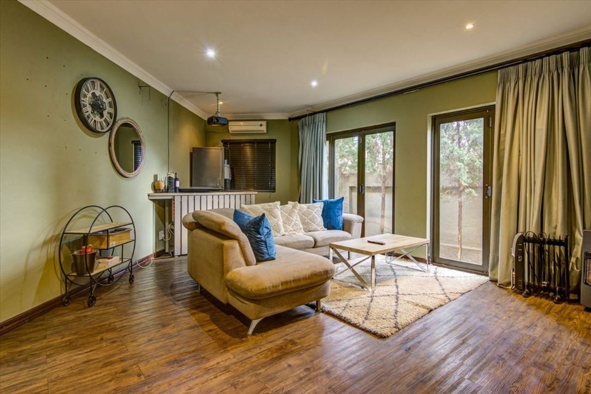 A comfortable living room featuring laminate flooring, recessed lighting, and direct access to the outdoor area through sliding glass doors.
