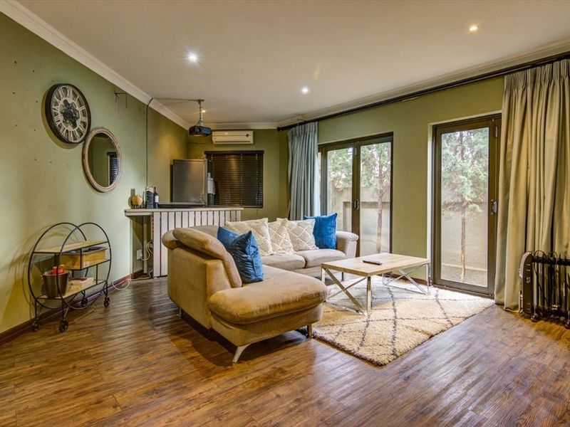 A comfortable living room featuring laminate flooring, recessed lighting, and direct access to the outdoor area through sliding glass doors.