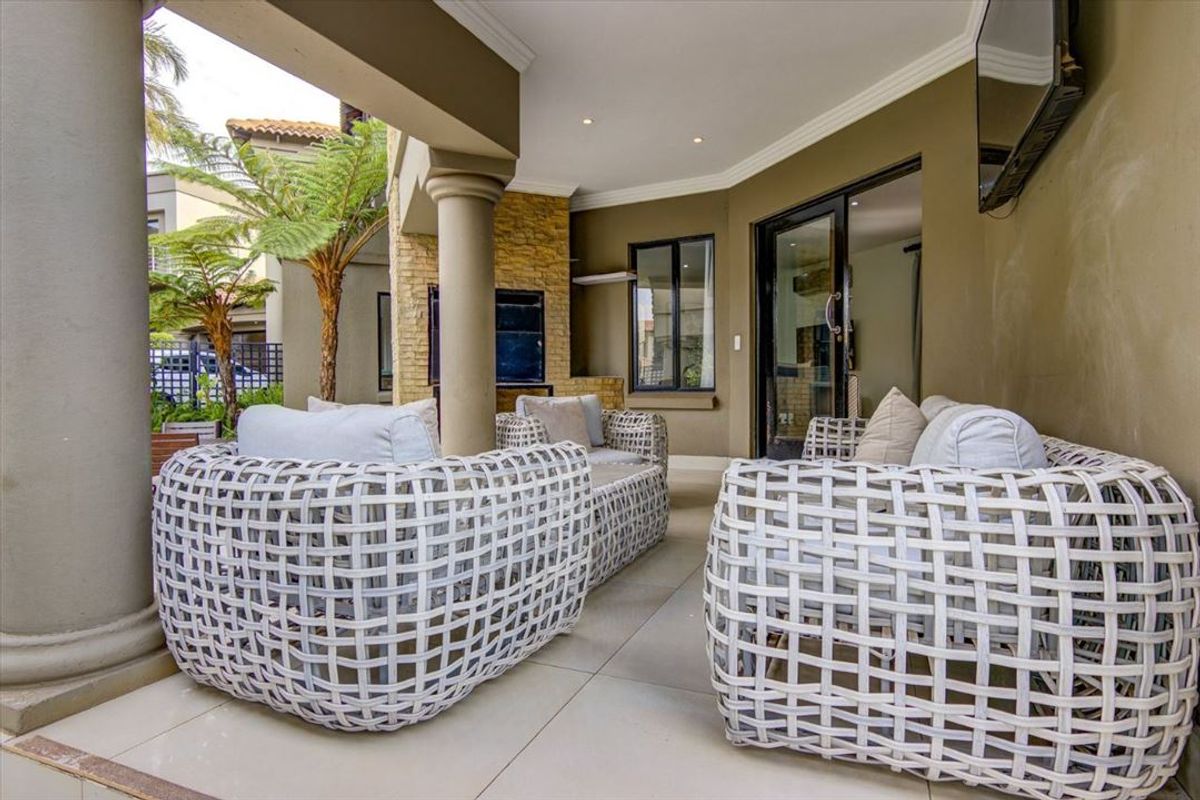 A covered patio area featuring tiled flooring, stone cladding accents, and concrete columns, providing a seamless transition to the interior living space.