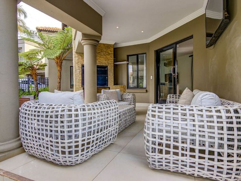 A covered patio area featuring tiled flooring, stone cladding accents, and concrete columns, providing a seamless transition to the interior living space.