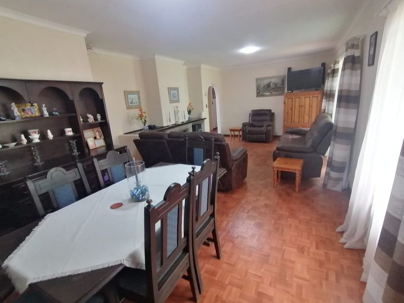 Spacious open-plan living and dining area featuring classic parquet flooring and a traditional archway, offering a versatile layout for family living.