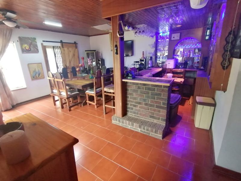 Open plan living and dining area featuring a built-in brick bar, timber ceiling, and ceramic tile flooring.