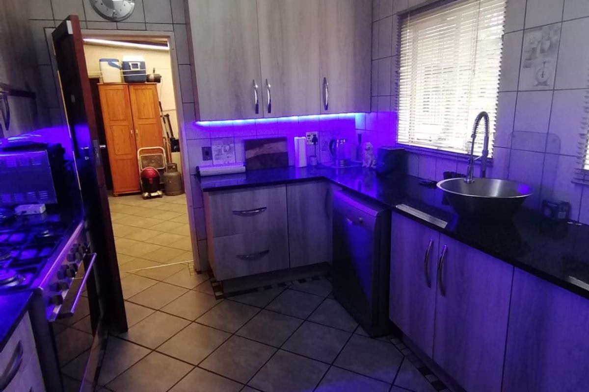 A functional kitchen featuring wood-look cabinetry, granite countertops, tiled flooring, and integrated under-cabinet lighting, providing a practical workspace with a classic layout.