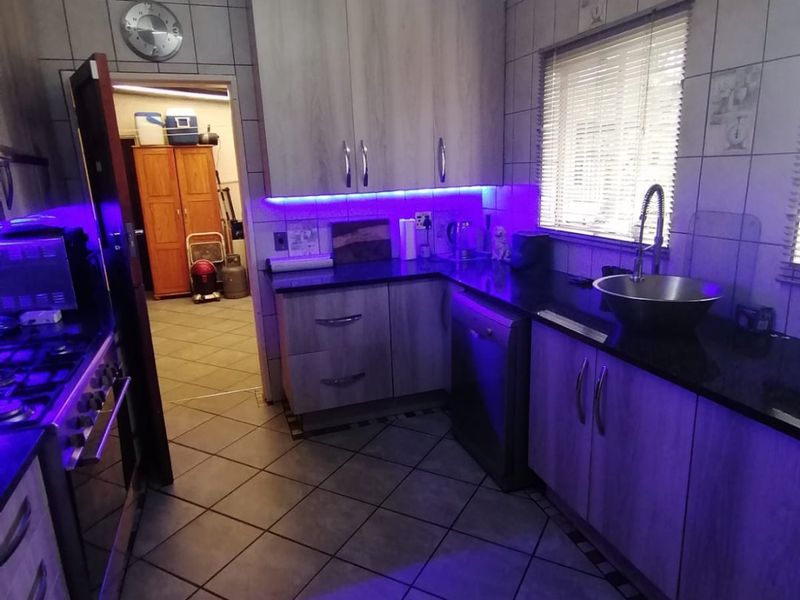 A functional kitchen featuring wood-look cabinetry, granite countertops, tiled flooring, and integrated under-cabinet lighting, providing a practical workspace with a classic layout.