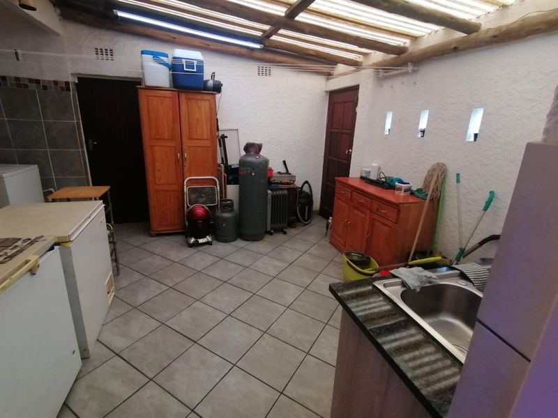 Functional laundry area featuring tiled flooring, built-in cabinetry, a stainless steel sink, and a translucent roof structure providing natural light.