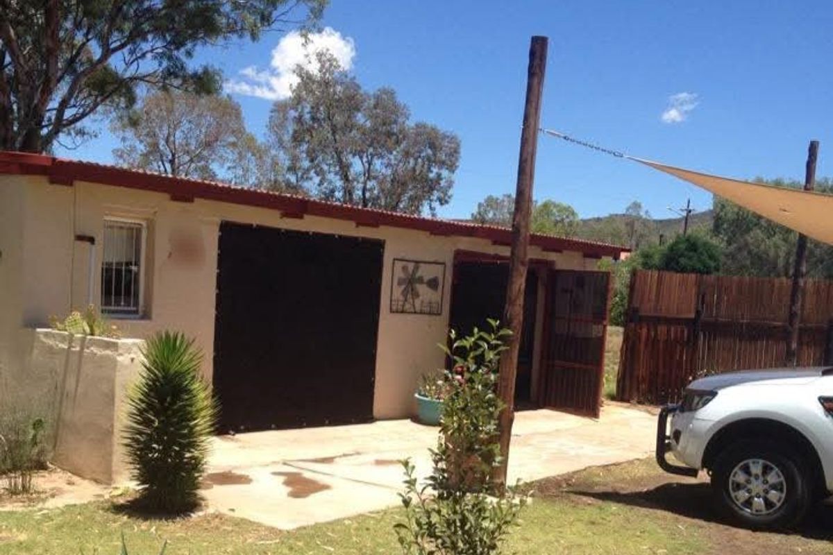 Rear exterior view of the property featuring a concrete patio area, shade sail, and perimeter timber fencing.