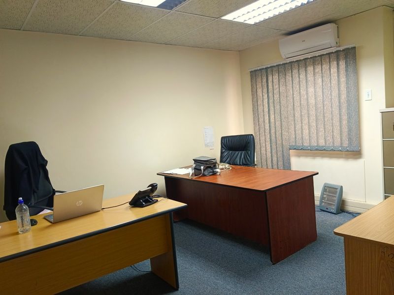 A functional commercial office space featuring a suspended ceiling, recessed lighting, split-system air conditioning, and carpeted flooring.