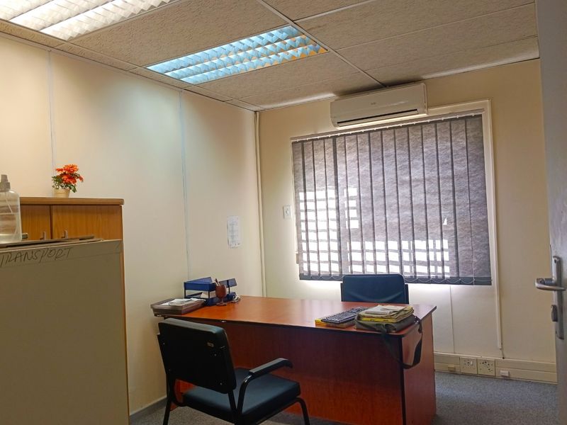 A functional office space featuring a suspended ceiling with recessed lighting, split-system air conditioning, vertical blinds, and carpeted flooring.
