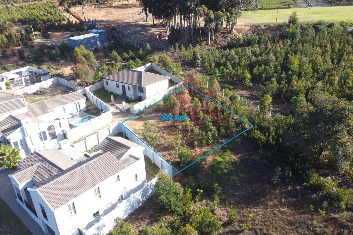Aerial view of a vacant residential plot measuring 335 square meters, situated within a developed estate with established boundary fencing and surrounding vegetation.