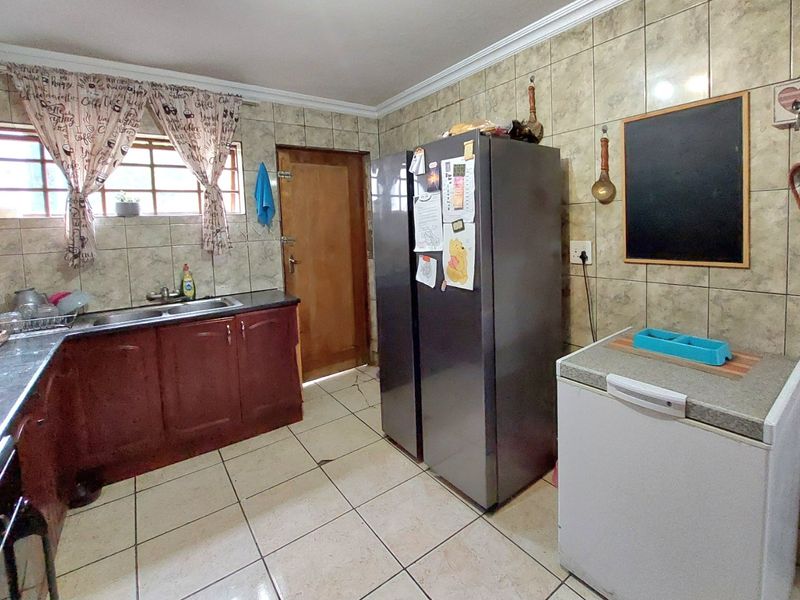 A functional kitchen featuring tiled walls and flooring, built-in cabinetry, and a double sink, offering a practical layout for daily meal preparation.