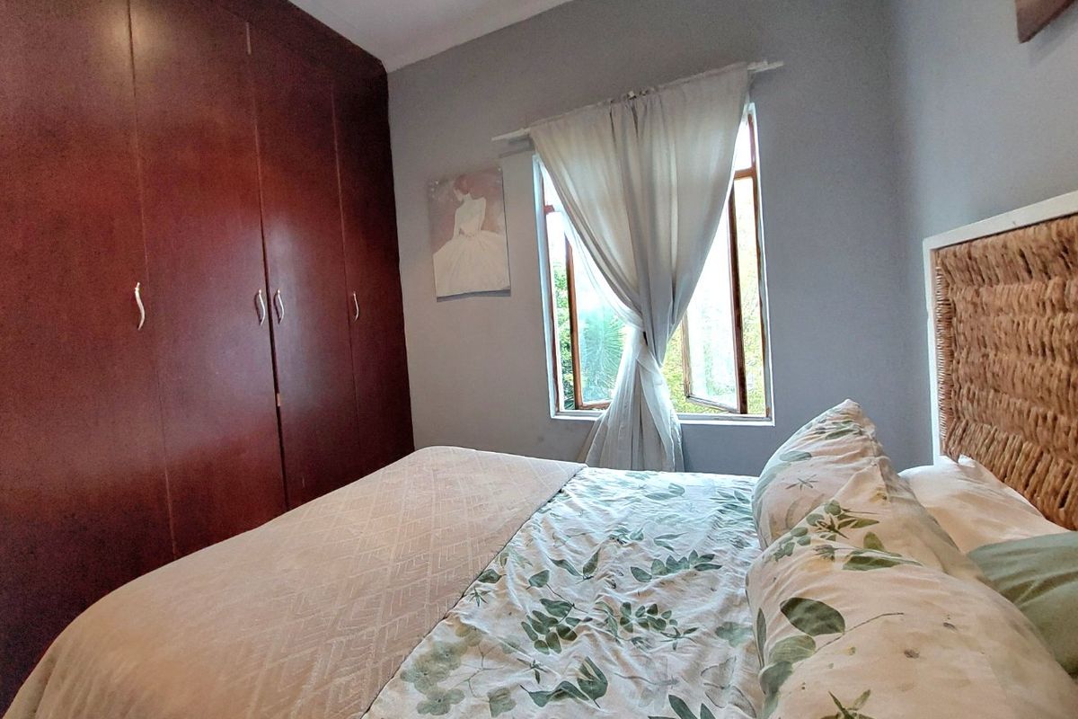 A bedroom featuring dark wood built-in cupboards and a casement window providing natural light.