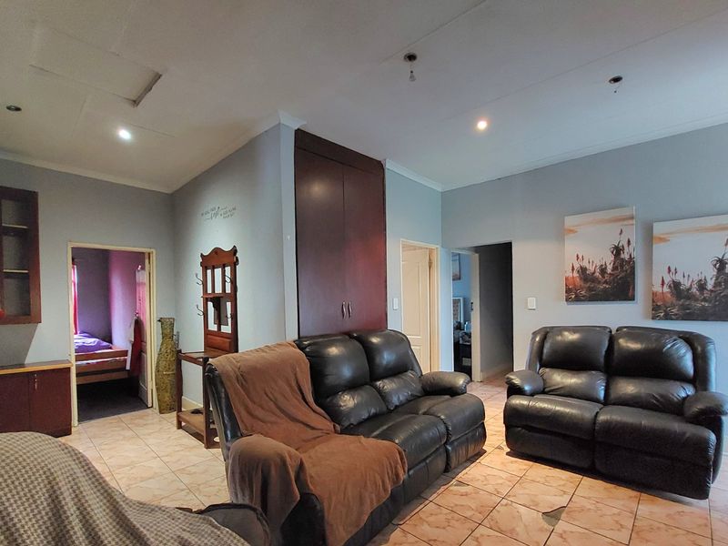 A living room featuring tiled flooring, built-in storage cabinetry, and recessed lighting, providing a functional space with potential for cosmetic updates.