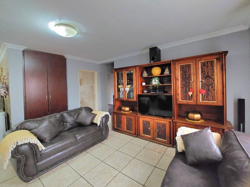 A living room featuring tiled flooring, a built-in storage cupboard, and coved ceiling details.