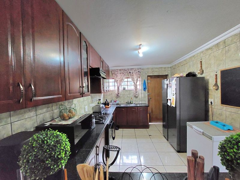 A functional kitchen featuring dark wood cabinetry, granite countertops, tiled backsplash, and tiled flooring, providing ample storage and workspace.