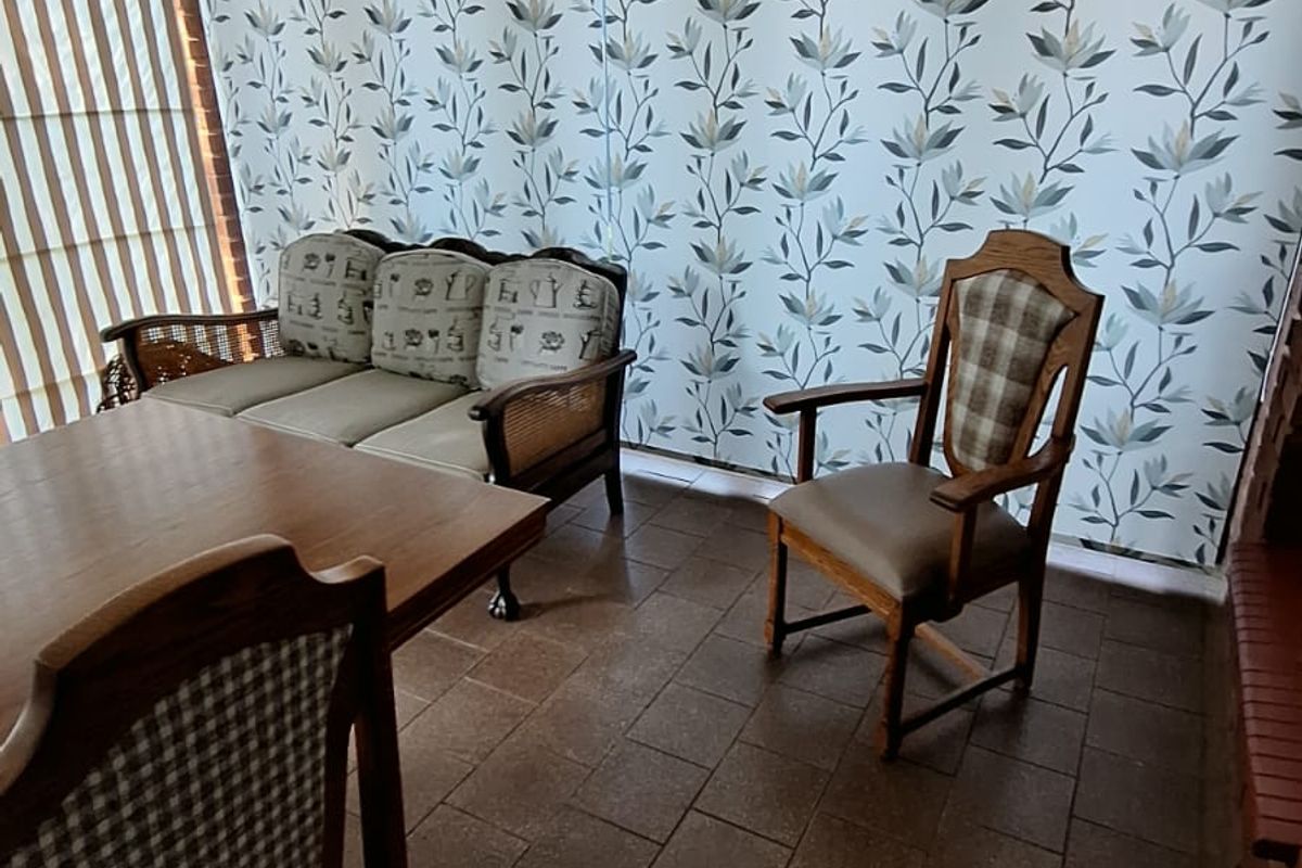 A living area featuring tiled flooring and decorative floral wallpaper, offering a functional space with potential for modern updates.