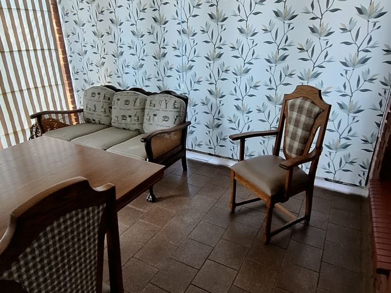 A living area featuring tiled flooring and decorative floral wallpaper, offering a functional space with potential for modern updates.