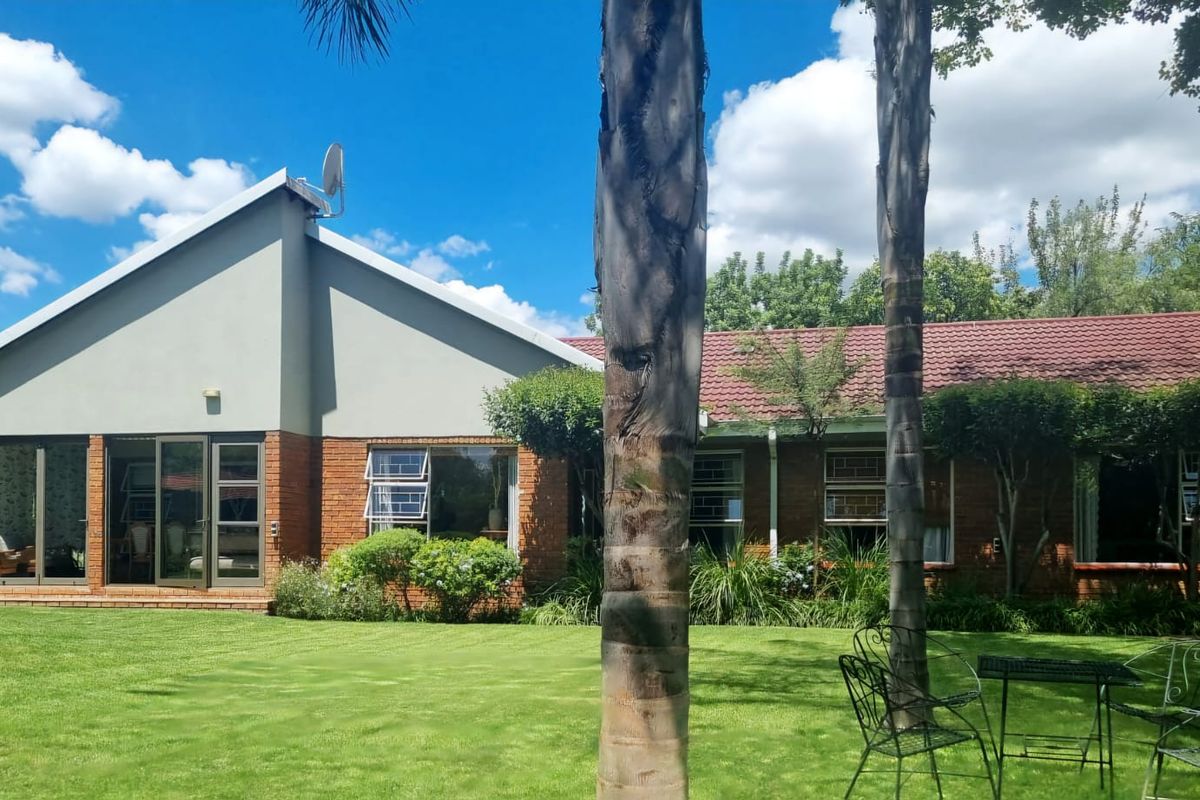 Rear view of the house featuring a brick facade, tiled roof, and large aluminium sliding doors opening onto a well-maintained garden.