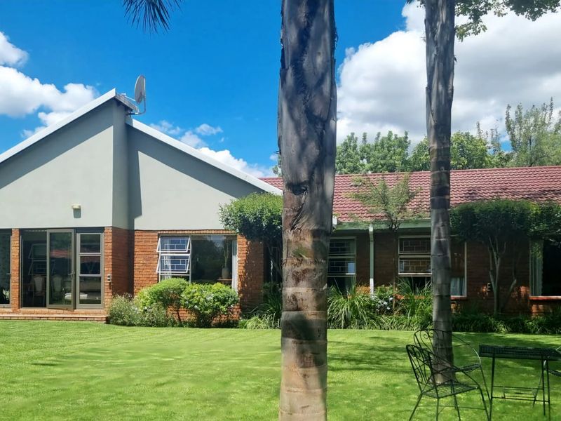 Rear view of the house featuring a brick facade, tiled roof, and large aluminium sliding doors opening onto a well-maintained garden.