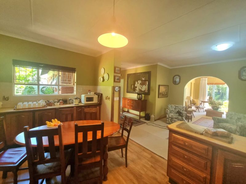 Open-plan living and kitchen area featuring wooden cabinetry, laminate flooring, and an arched transition to the adjacent living space.