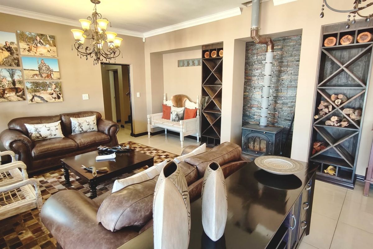 Spacious living room featuring a stone-clad fireplace, built-in wooden shelving units, tiled flooring, and elegant crown molding.