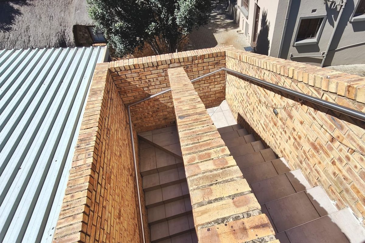 An outdoor brick staircase with stainless steel handrails providing access between levels, featuring tiled steps and a durable construction.