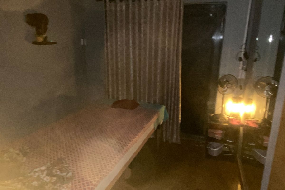 A dimly lit room featuring a bed and curtained window, currently used as a private space.