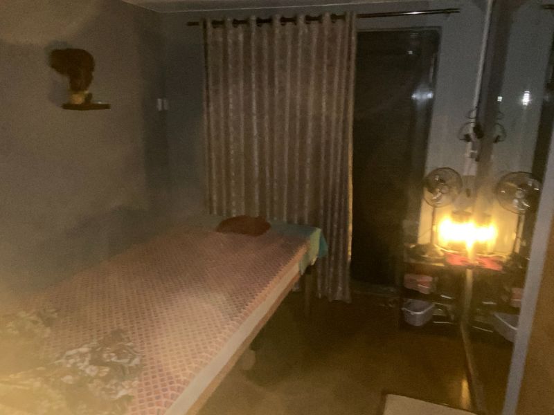 A dimly lit room featuring a bed and curtained window, currently used as a private space.
