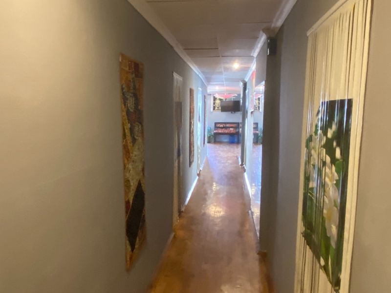 A long interior hallway featuring laminate flooring and a suspended ceiling with recessed lighting.