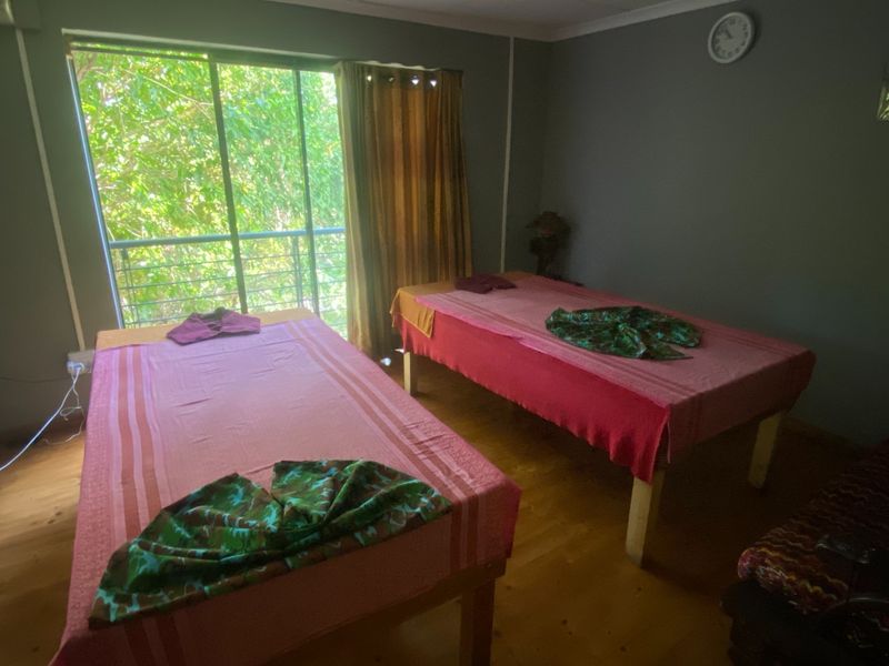 A treatment or therapy room featuring timber flooring and a large sliding glass door providing natural light and garden views.