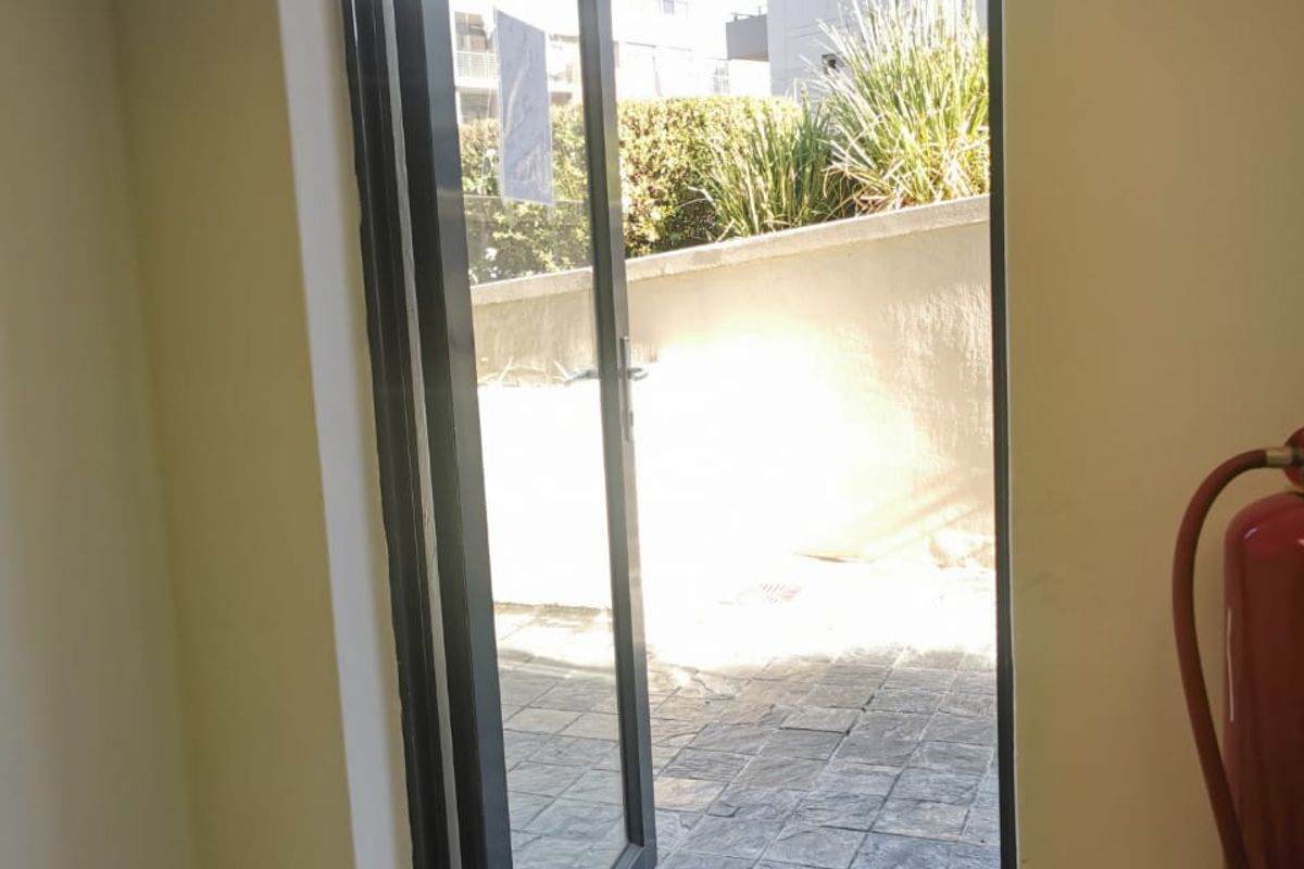 An interior entry point featuring a glass door opening onto a paved outdoor patio area with a wall-mounted fire extinguisher.
