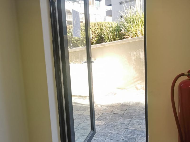 An interior entry point featuring a glass door opening onto a paved outdoor patio area with a wall-mounted fire extinguisher.