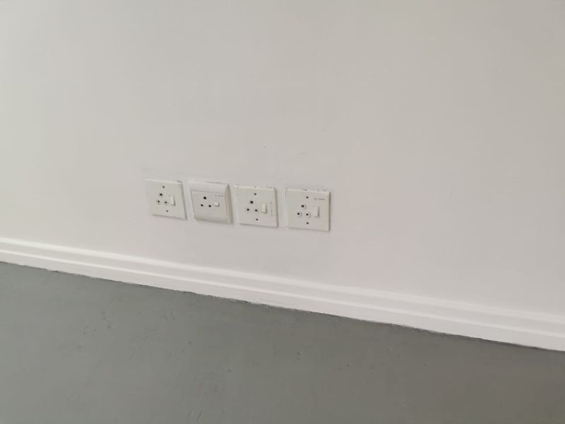 A close-up view of a white wall featuring a row of four electrical power outlets and baseboard trim.