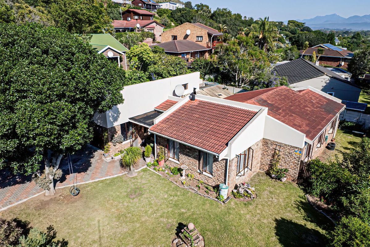 Aerial view of a residential property featuring a brick facade, tiled roof, paved driveway, and a well-maintained garden area.