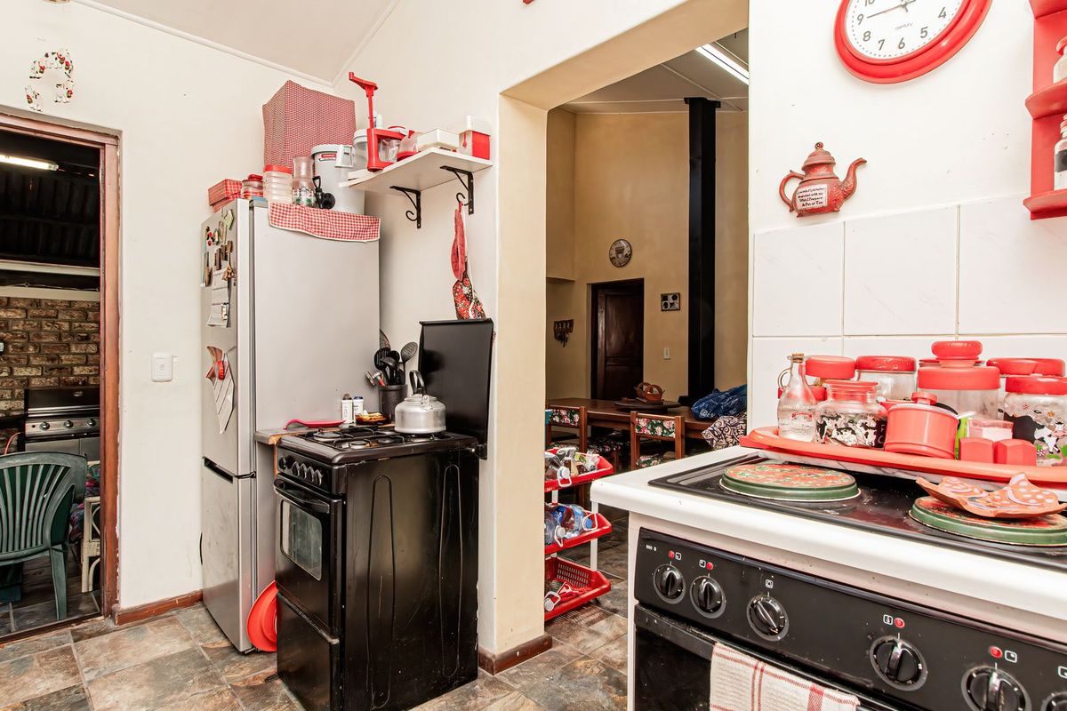 A functional kitchen area featuring slate flooring, tiled splashbacks, and a freestanding stove, with an open transition to an adjacent living space.