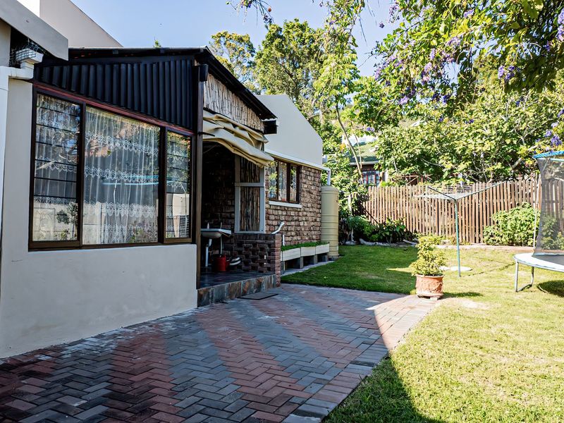 Rear view of the property featuring a paved patio area, brick exterior walls, and a private garden with timber fencing.
