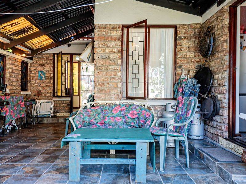 A covered outdoor patio area featuring exposed brick walls, tiled flooring, and an exposed beam ceiling, providing a rustic space for outdoor living.