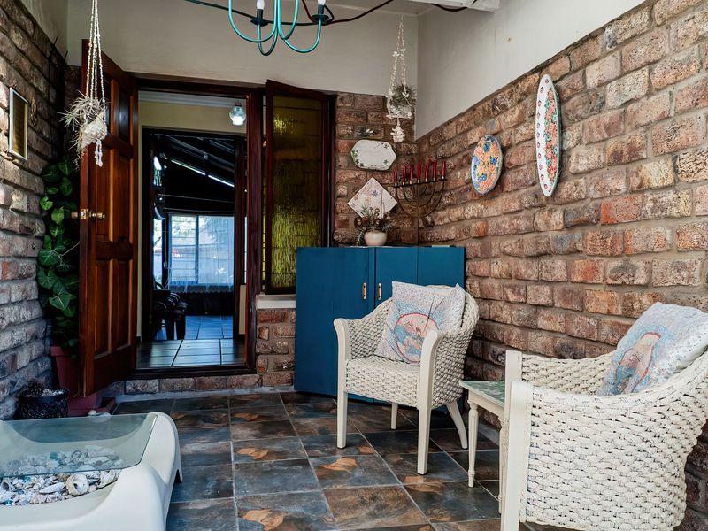 A covered patio area featuring rustic exposed brick walls and durable tiled flooring, providing a charming transition space between the interior and exterior.