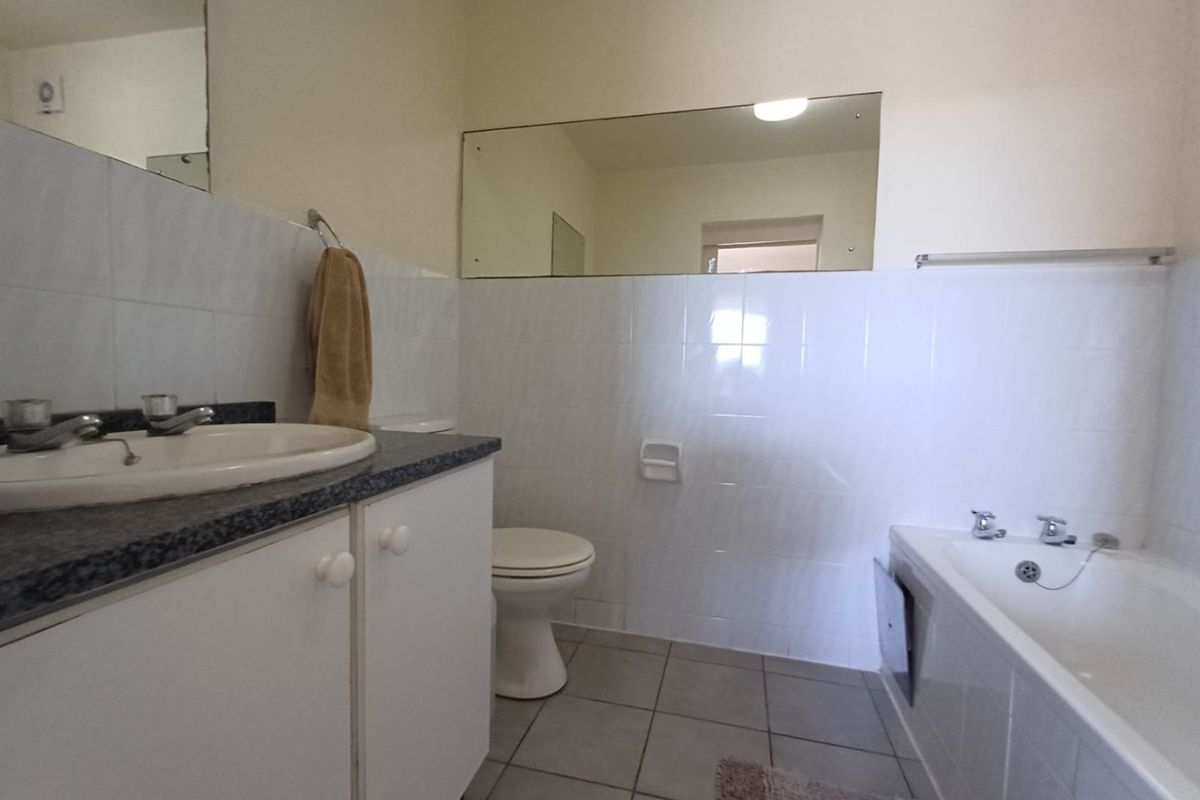 A functional bathroom featuring a vanity with basin, a standard bathtub, tiled walls, and tiled flooring, requiring minor cosmetic updates.