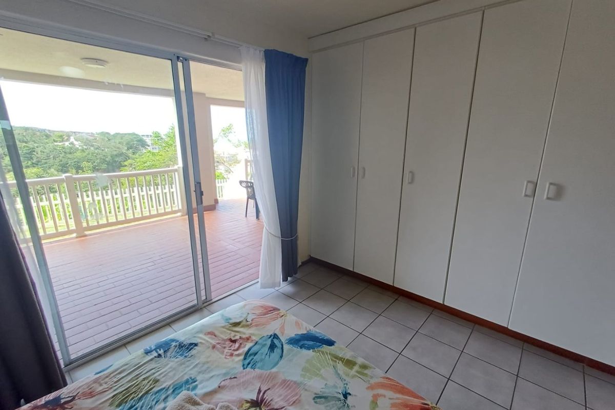Bedroom featuring built-in cupboards, tiled flooring, and a sliding glass door providing direct access to a private balcony with scenic views.