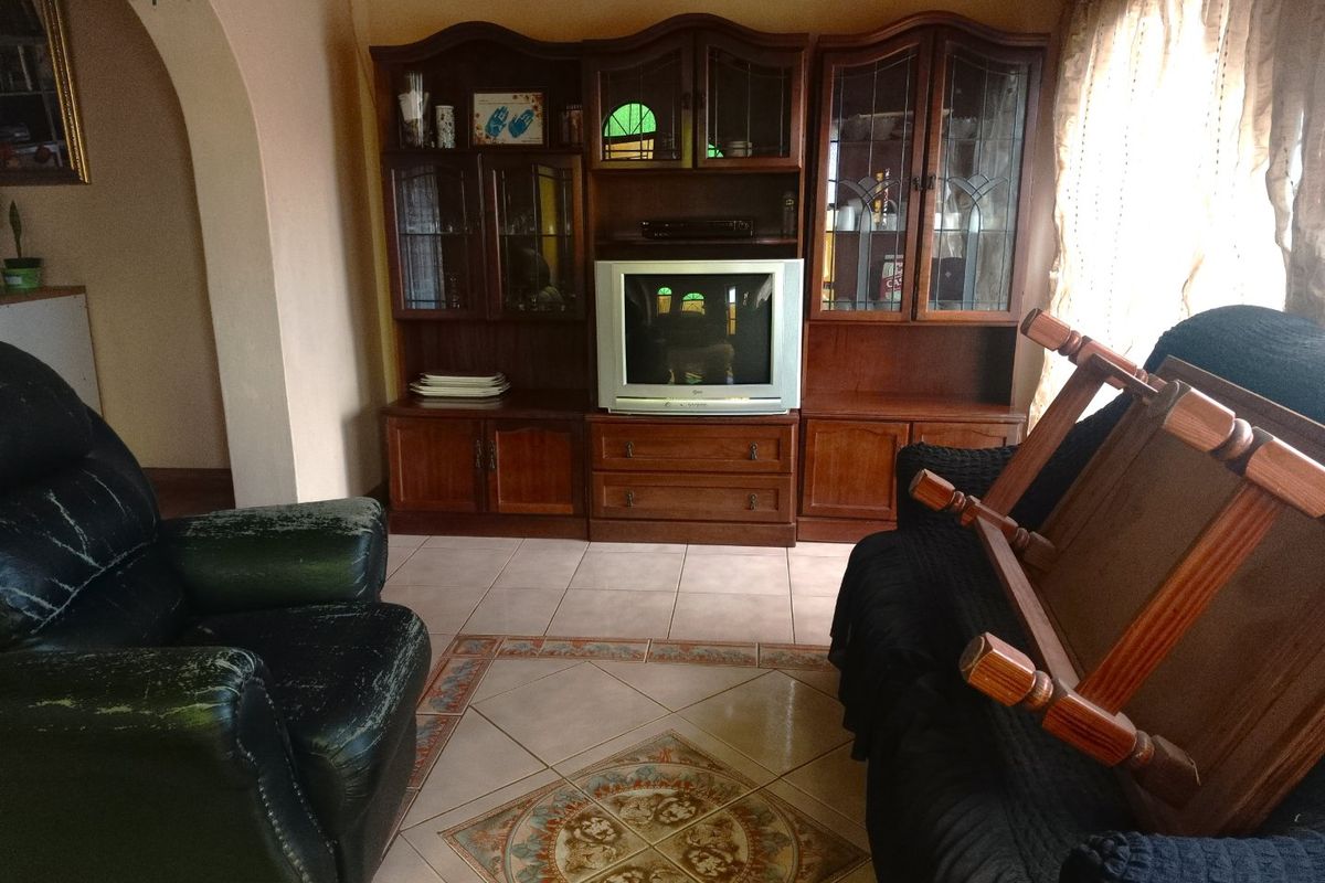A living room featuring ceramic tiled flooring with a decorative central inlay and an arched entryway leading to adjacent spaces.