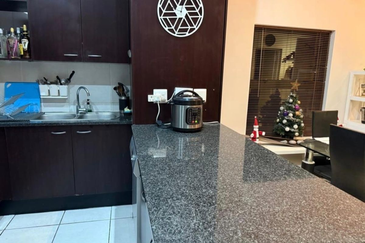 A functional kitchen featuring dark wood cabinetry, granite countertops, a breakfast bar, and tiled flooring, providing a practical workspace for daily meal preparation.