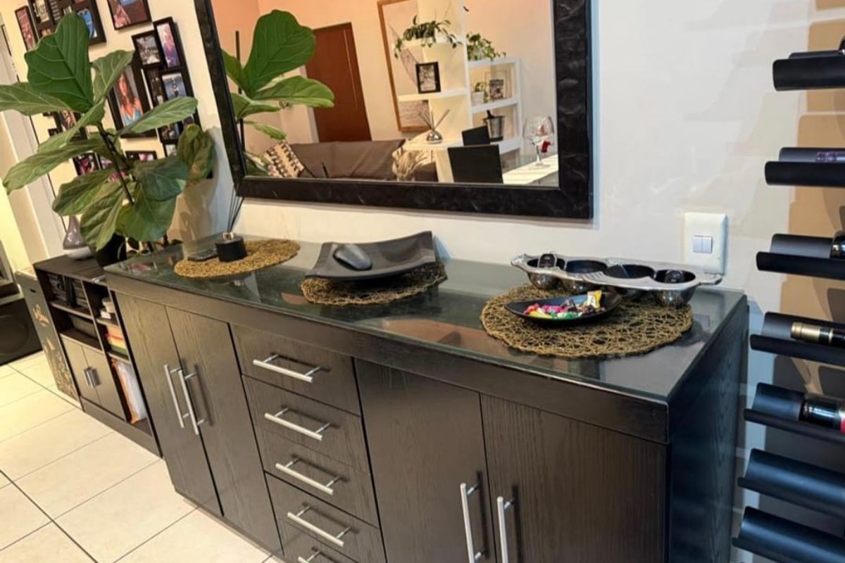 A living area featuring dark wood built-in cabinetry with a glass top, tiled flooring, and a wall-mounted wine rack.