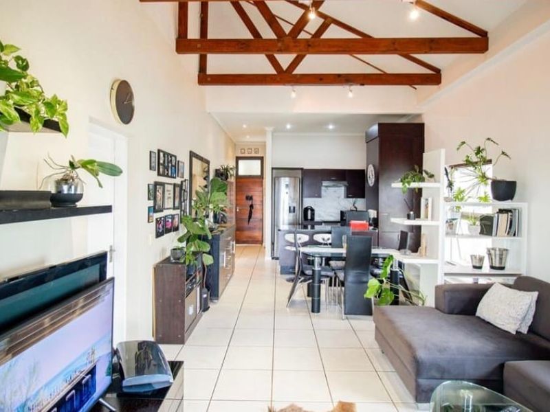 Open-plan living and kitchen area featuring high ceilings with exposed timber trusses, tiled flooring, and modern built-in cabinetry.