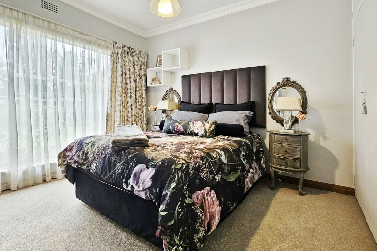 A well-maintained bedroom featuring neutral carpet, built-in wardrobe storage, and large windows with curtain tracks, offering a comfortable and functional living space.
