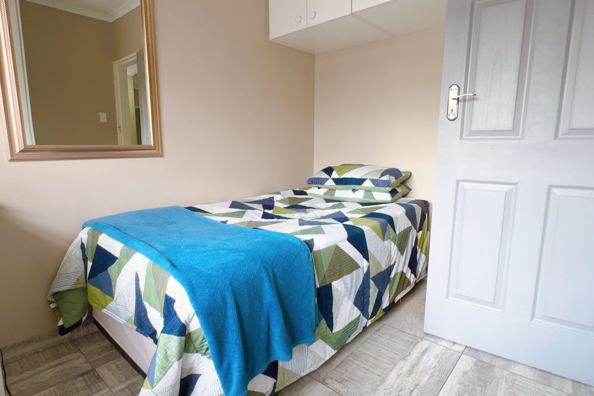 A compact bedroom featuring tiled flooring, built-in overhead storage cabinetry, and a classic panel door.