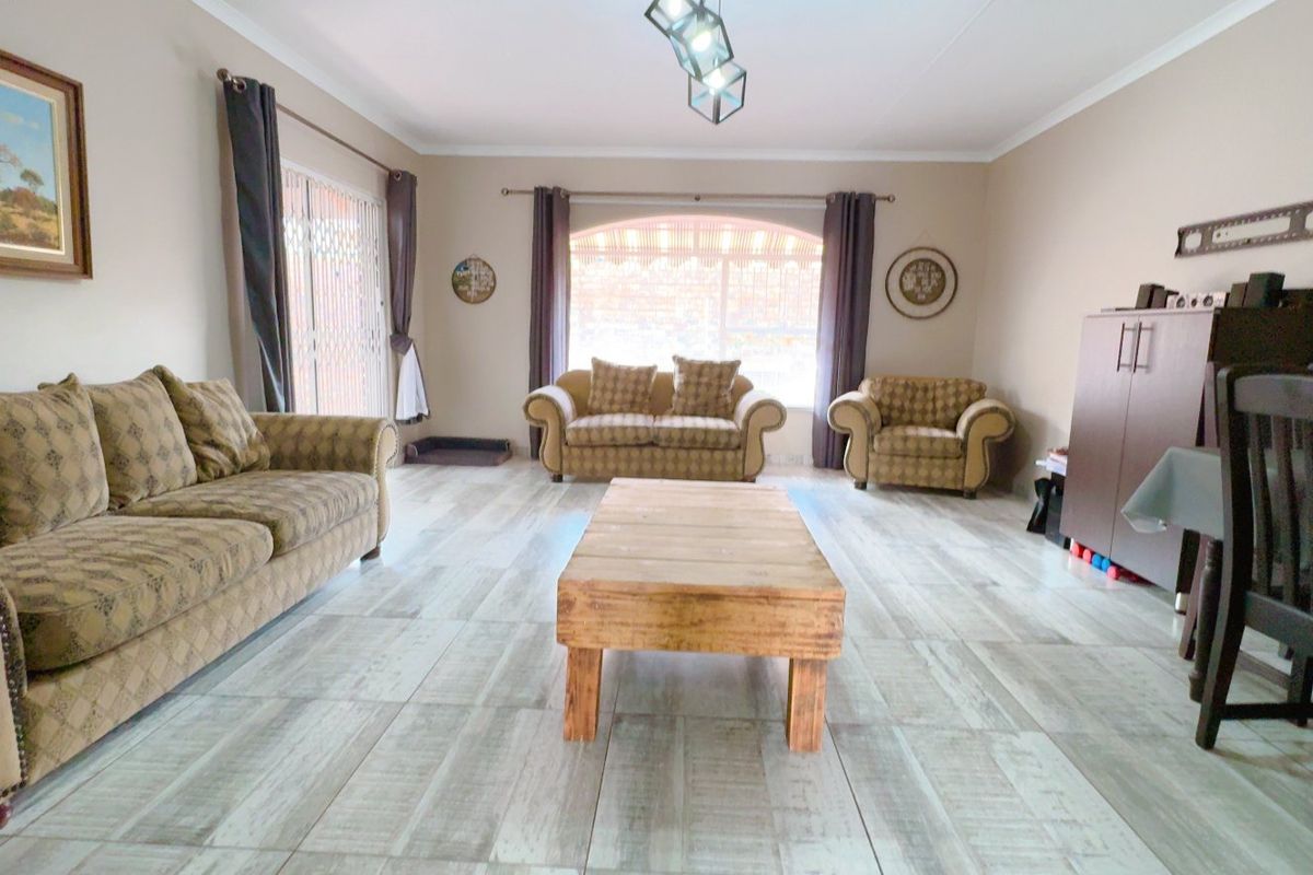 Spacious living room featuring light-toned tiled flooring, an arched window, and a sliding door providing access to the exterior.