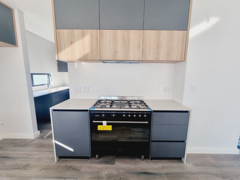 Modern kitchen featuring two-tone cabinetry, stone countertops, and a built-in gas stove with an integrated extractor fan.