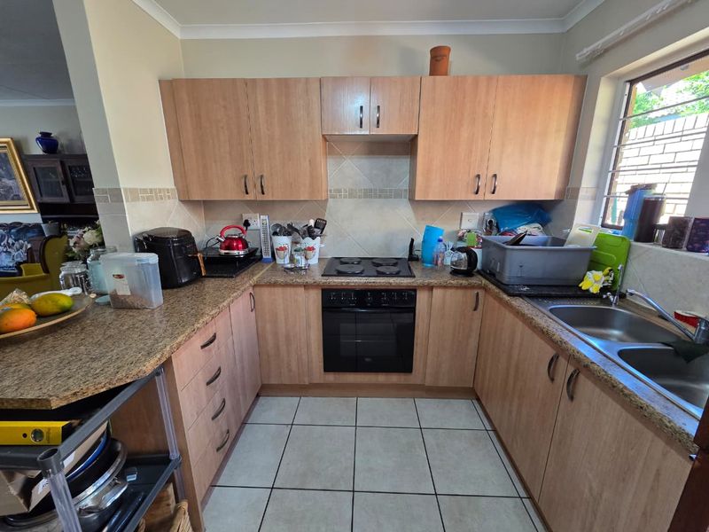Functional kitchen featuring laminate cabinetry, granite countertops, built-in oven, electric hob, and a double bowl stainless steel sink with tiled backsplash.