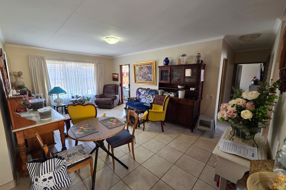 A spacious living area featuring neutral tiled flooring and natural light through large windows, offering a versatile layout for comfortable daily living.