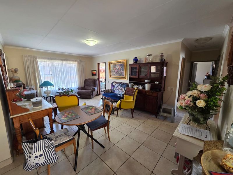 A spacious living area featuring neutral tiled flooring and natural light through large windows, offering a versatile layout for comfortable daily living.
